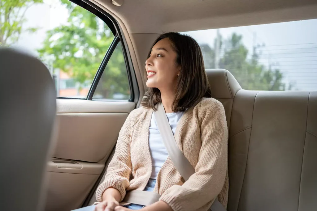 Happy woman sitting in back of car